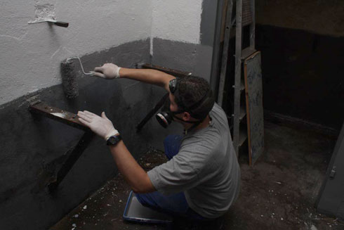 Nico qui applique la couche de gris sur le soubassement du mur.
