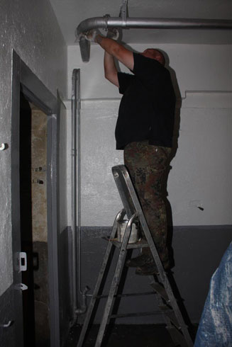 Eric qui peint les supports des tuyaux de ventilation.